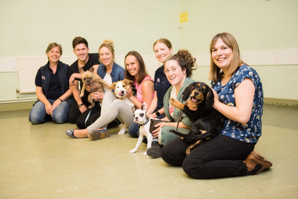 Puppy School tutor and owners kneeling holding puppies